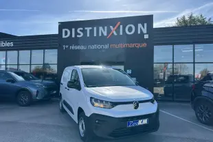 Vue 3/4 avant d'un Citroën Berlingo blanc Icy avec calandre noire, stationné devant un showroom Distinxion.