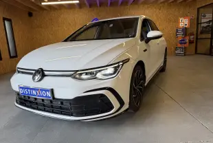 Volkswagen Golf 2.0 TDI 150 DSG7 R-Line blanc vue 3/4 avant en intérieur avec jantes noires et phares allumés.
