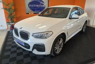 BMW X4 blanc en 3/4 avant droit dans un showroom avec jantes alliage et calandre chromée distinctive.