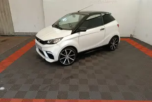 Vue 3/4 avant droite de l'AIXAM AMBITION 0.5 CITY COUPE GTI blanche avec toit noir et jantes alliage noires.