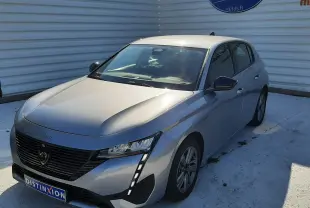 Peugeot 308 III Hybrid gris Artense vue 3/4 avant droit, avec calandre noire et feux LED verticaux distinctifs.