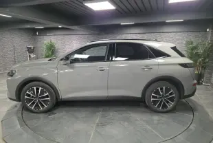 Vue latérale droite du DS7 Crossback gris métallisé 2025 avec jantes alliage noires et toit noir brillant.