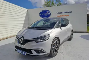 Renault Scénic IV gris platine avec toit noir, vue 3/4 avant droit, stationné devant un mur blanc.