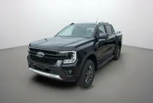 Ford Ranger 3.0 V6 Wildtrak Plus noir agate vu en 3/4 avant droit, avec jantes alu et barres de toit visibles.