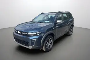 SUV Dacia Bigster bleu indigo en 3/4 avant droit, avec barres de toit et jantes alu 17 pouces visibles.