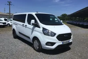 Ford Transit Custom Kombi blanc vu en 3/4 avant droit, avec vitres arrière teintées et jantes acier.