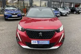 Vue avant d’un Peugeot 2008 rouge métal 2022 avec calandre noire et feux LED verticaux, sur parking de véhicules d’occasion.