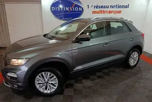 Volkswagen T-Roc gris foncé vue de profil droit en intérieur, avec jantes alliage et barres de toit chromées.