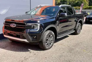 Ford Ranger 3.0 V6 Wildtrak Plus noir agate vu en 3/4 avant droit avec jantes alu et barres de toit visibles.