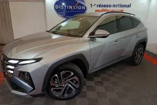 Vue 3/4 avant droit du Hyundai Tucson gris clair 2025 avec jantes alliage et calandre distinctive en showroom.